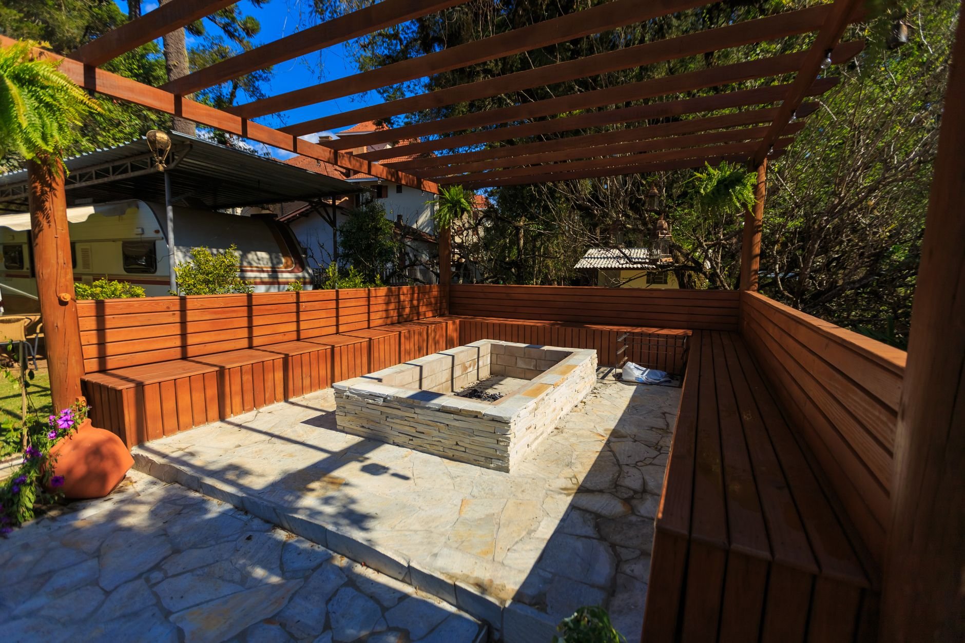 Inviting patio with a stone fire pit and wooden benches under a pergola